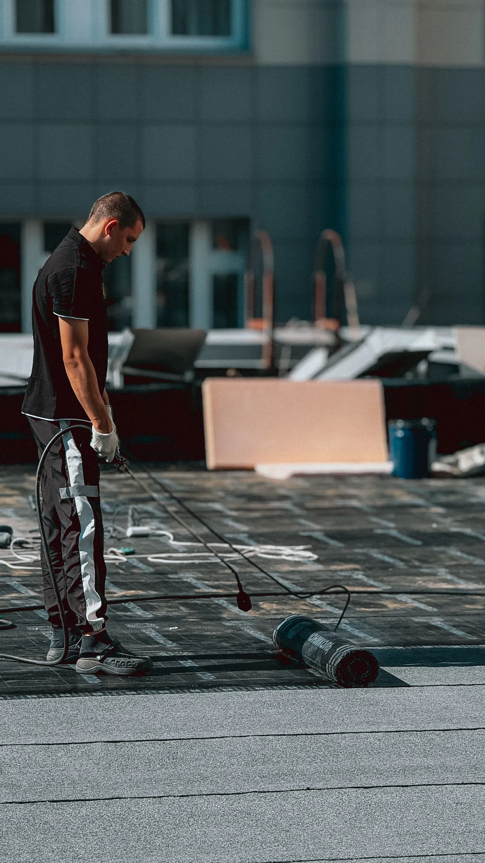 Worker applying a waterproofing layer to a flat roof