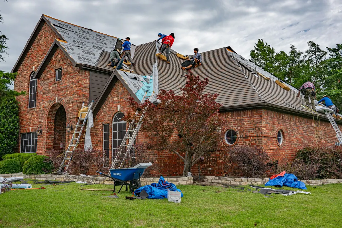 Roofers replacing shingles on a brick home