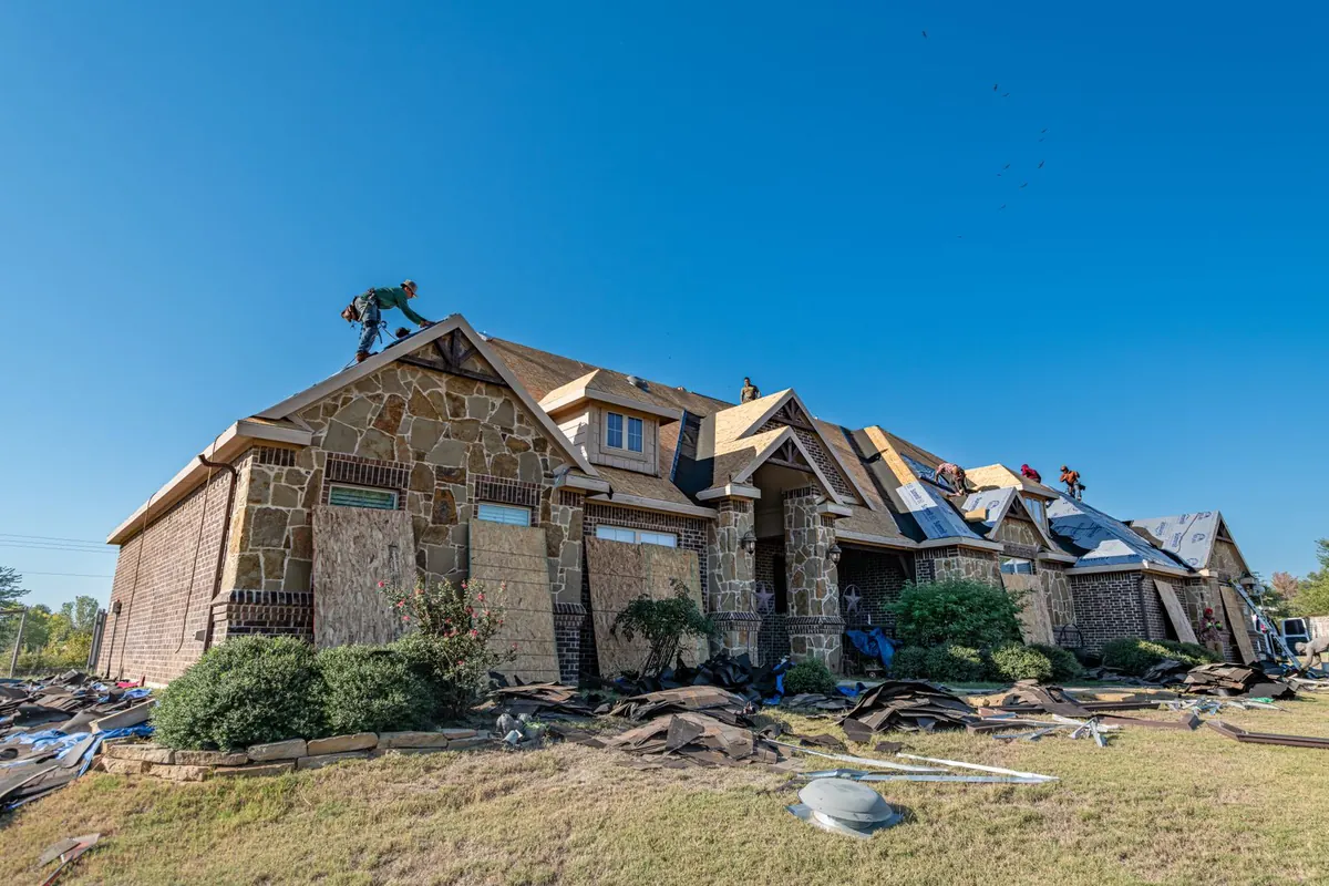 Roof replacement in progress on a brick home