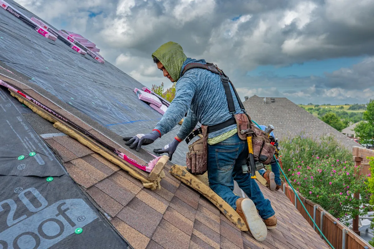 Roofers installing shingles on a residential roof