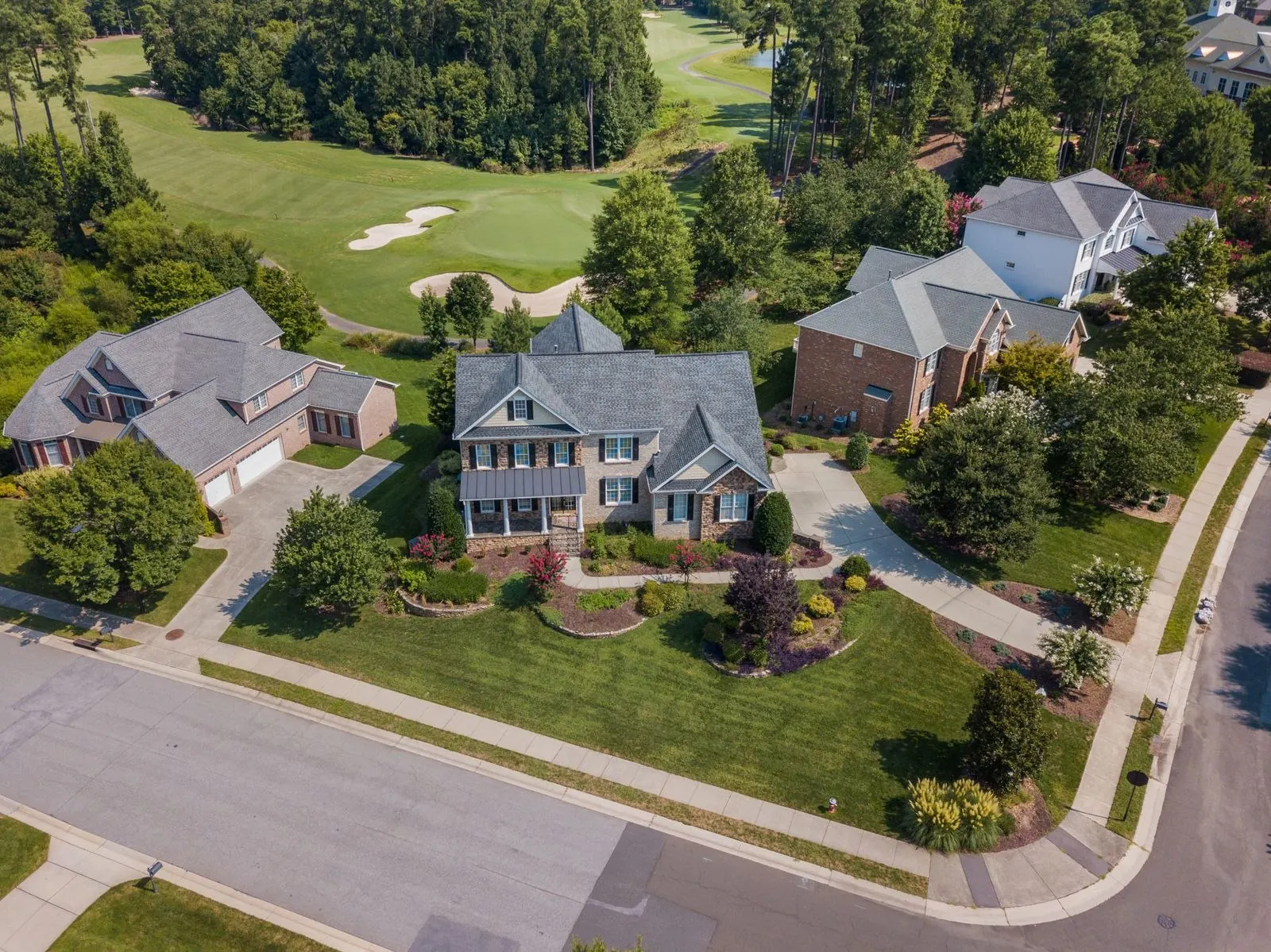 Homes and shingle roofs among mature trees